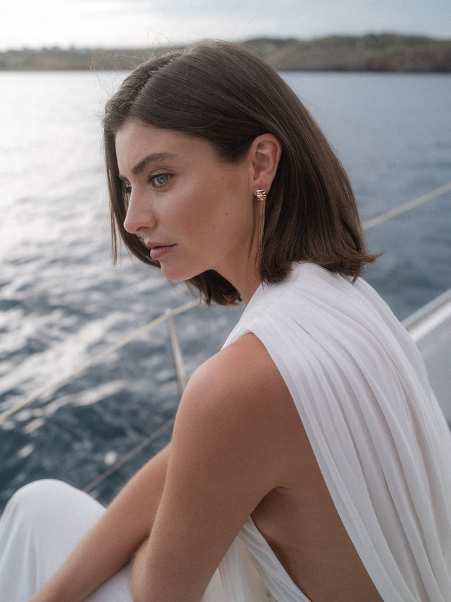 PURELEI Allure Ohrringe in Roségold mit filigranen Kettensträngen, getragen vor maritimem Hintergrund – elegant und feminin.