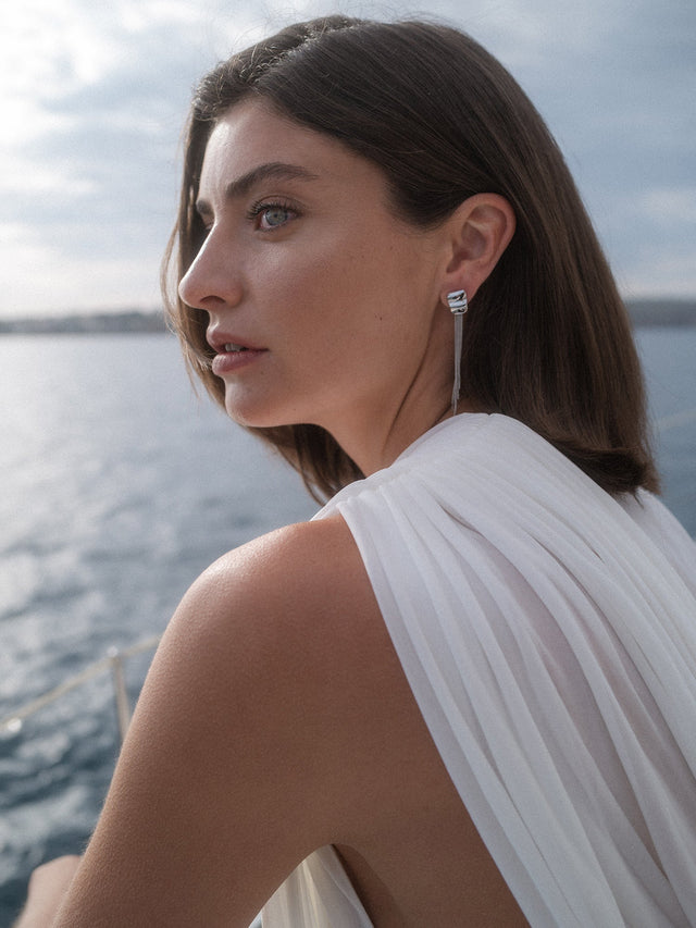 PURELEI Allure Ohrringe aus silberfarbenem Edelstahl mit filigranen Ketten, elegant am Meer getragen