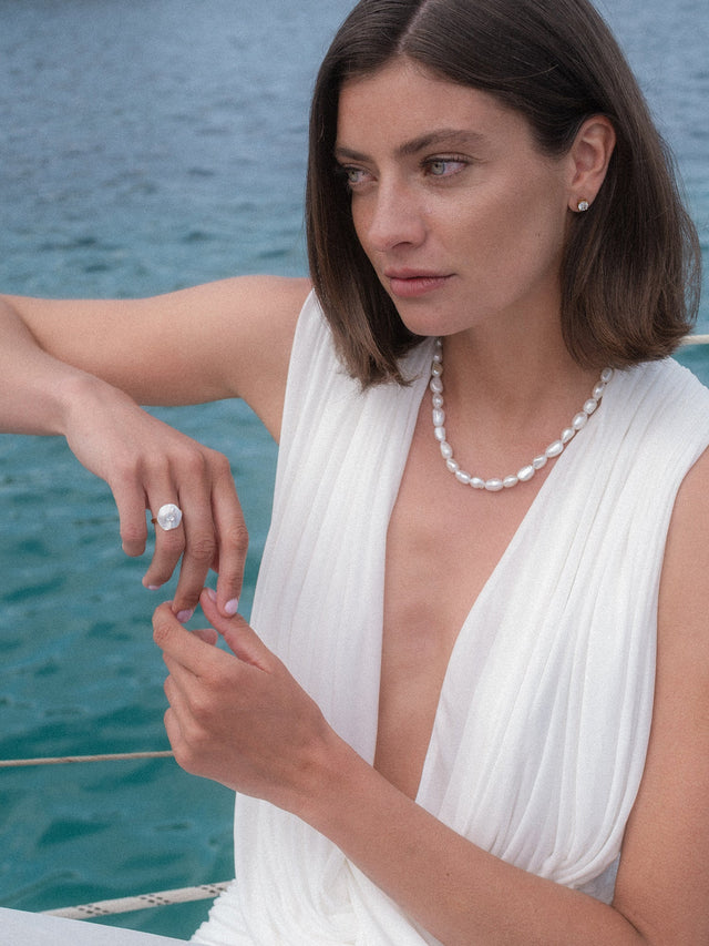 Allure Ring mit Stein, vergoldet, Muschel-Blütenmotiv mit weißem Zirkonia, getragen am Meer, PURELEI Stil