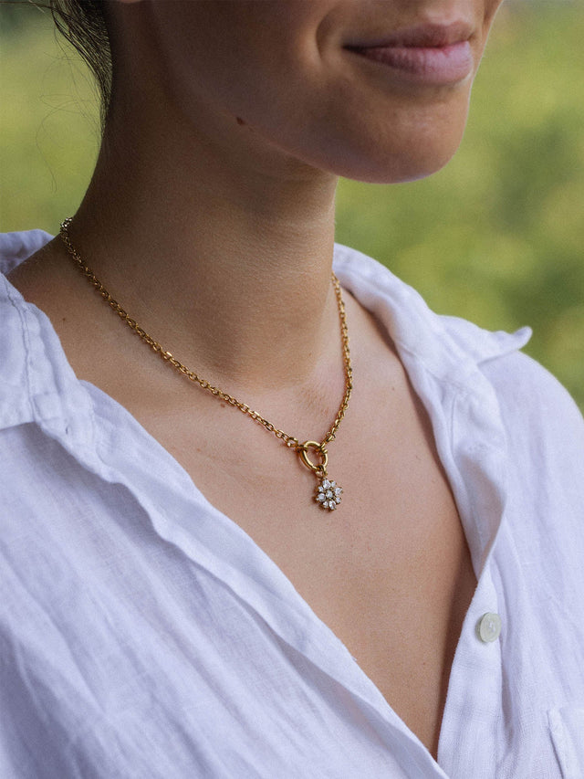 PURELEI Blossom Charm Halskette aus 18K Gold mit funkelndem Zirkonia-Blütenanhänger, warm und elegant getragen.