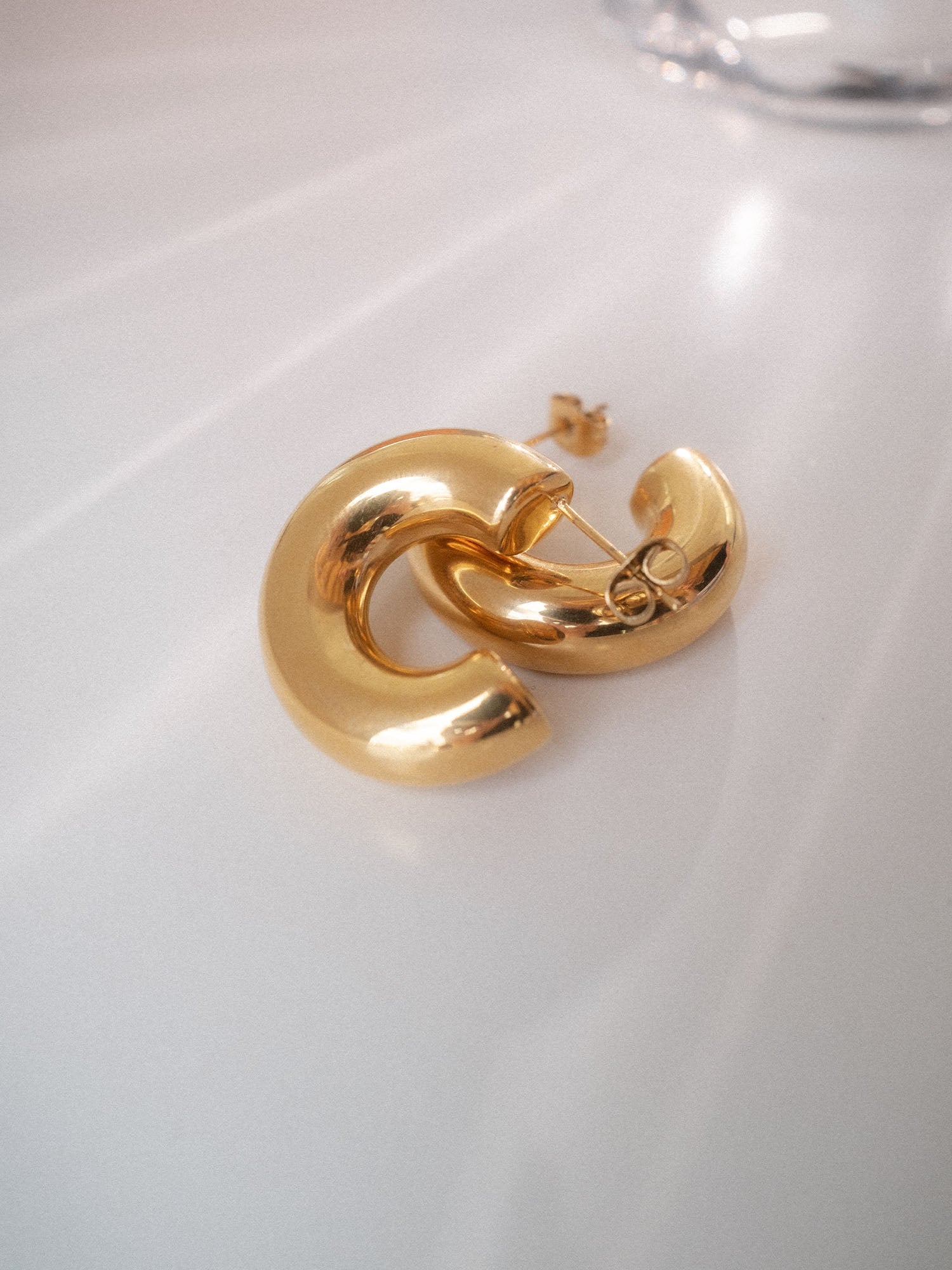 PURELEI Small Stellar Glow Ohrringe aus goldenem Edelstahl, elegant schimmernd auf hellem Untergrund.