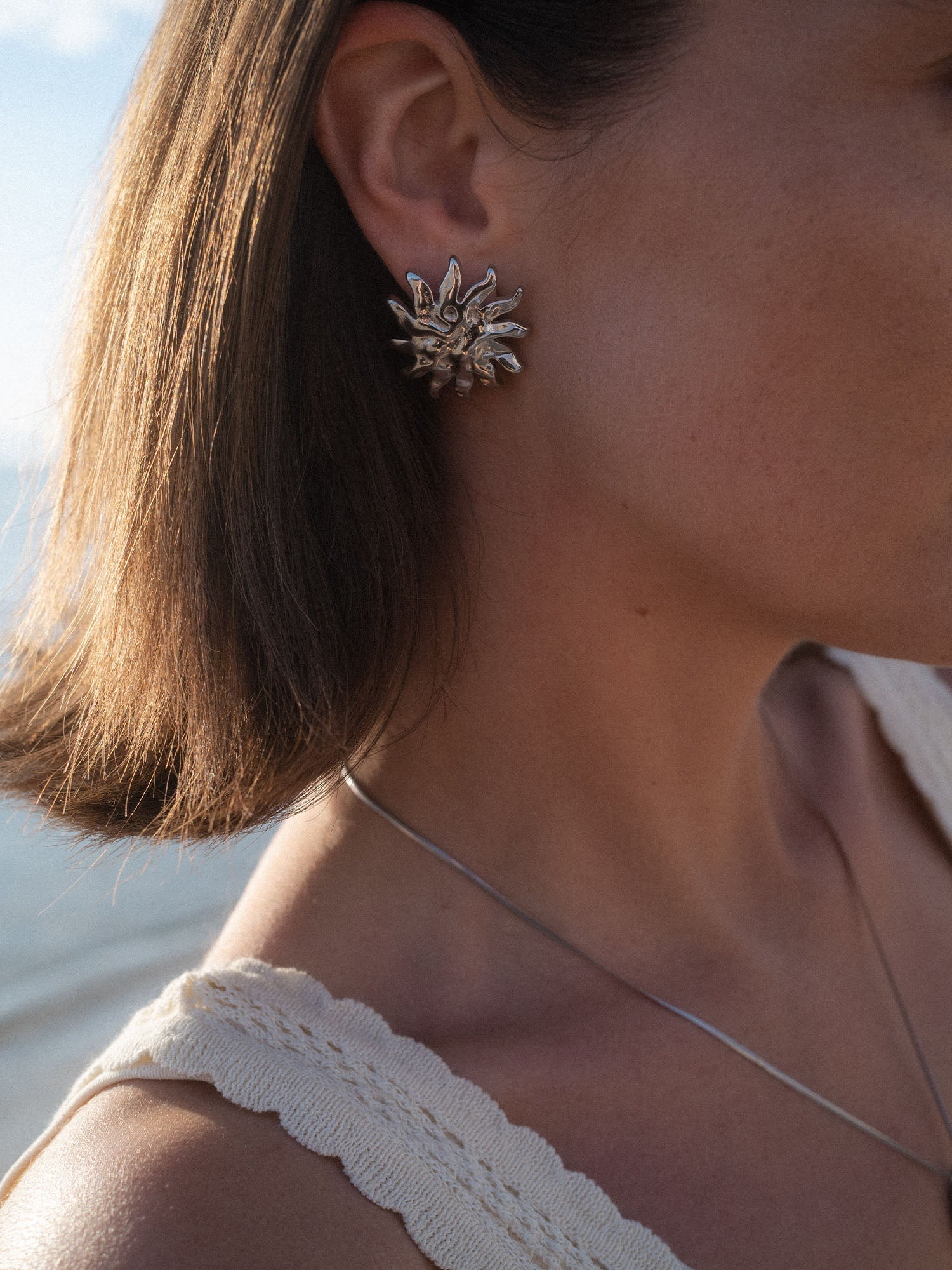 Silberne Iconic Sun Ohrringe mit strukturierter Oberfläche, getragen am Ohr in natürlichem Sonnenlicht, PURELEI.